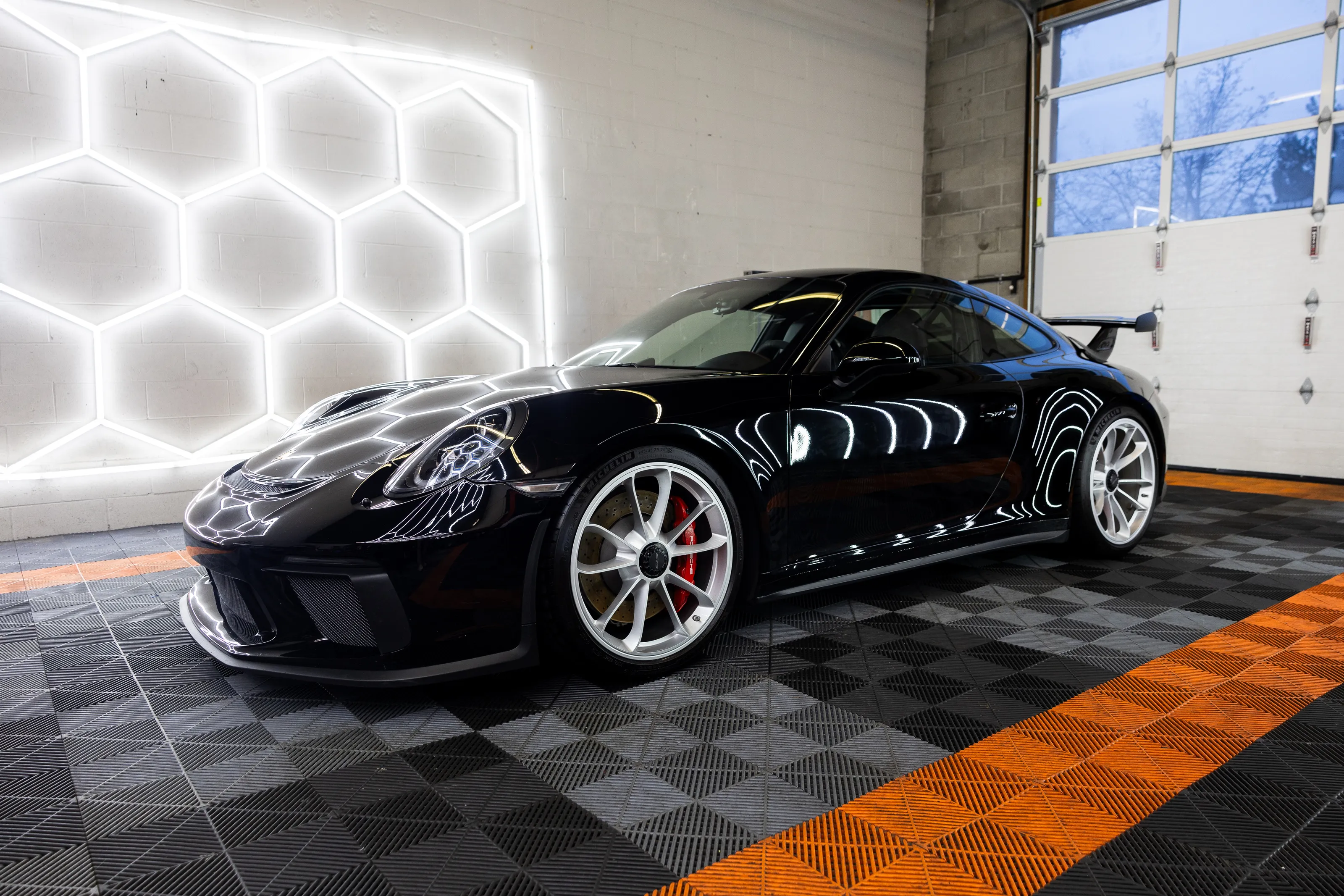 Black Porsche 911 GT3 under the hexagon lights in the Dutchman Customs bay